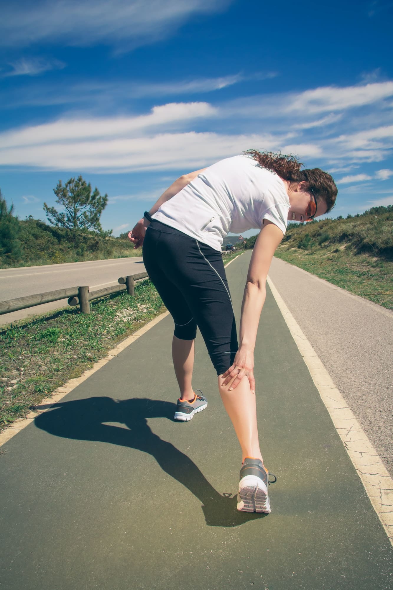 Athletic woman suffering pain in leg calf by cramp